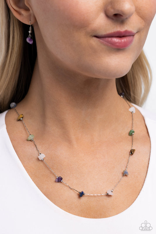 <p>Infused along a silver chain, tiger's eye, jade, white, amethyst, lapis, and light pink stones, bordered by silver beads, sporadically dot around the collar for a simple, stony statement. Features an adjustable clasp closure. As the stone elements in this piece are natural, some color variation is normal.</p> <p><i> Sold as one individual necklace. Includes one pair of matching earrings.</i></p>