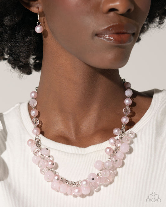 <p>Infused along a classic silver chain, faceted baby pink beads in various opacities, and shimmer cascade in a capricious pattern around the neckline. Features an adjustable clasp closure.</p> <p><i> Sold as one individual necklace. Includes one pair of matching earrings. </i></p> <br><b> Get The Complete Look! </b> <br>Bracelet: "Pearl Protagonist - Pink" (Sold Separately)