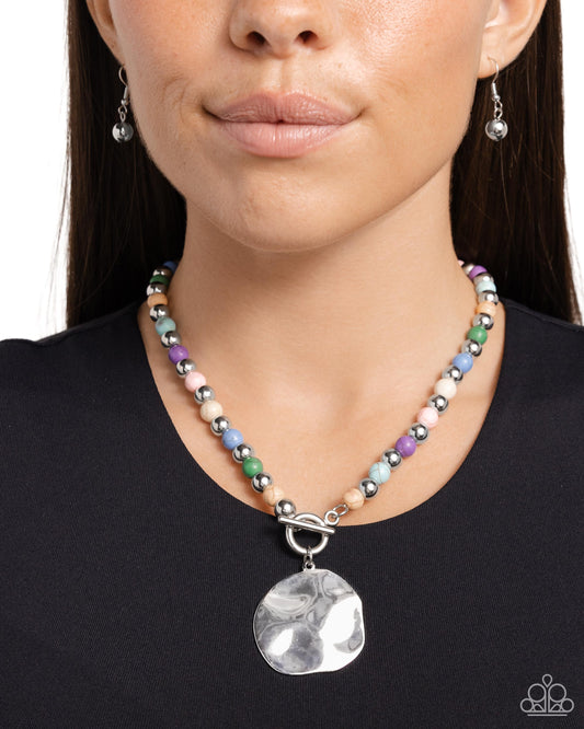 <p>Infused along an invisible string, colorful stones alternate with high-sheen silver beads as they connect through a toggle closure. A hammered oversized concaved silver disc cascades from the colorful strand for additional eye-catching detail. Features a toggle closure. As the stone elements in this piece are natural, some color variation is normal.</p> <p><i> Sold as one individual necklace. Includes one pair of matching earrings.</i></p>