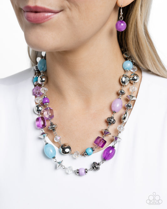 Featuring a variety of opacities, a collection of purple, Capri Blue, and Pastel Lilac beads join various textured silver beads and faceted clear beads along the neckline in two layers for a playfully, colorful look. Features an adjustable clasp closure.  Sold as one individual necklace. Includes one pair of matching earrings. 