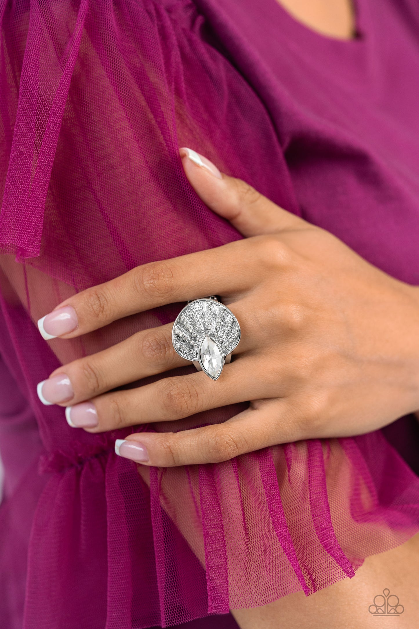An asymmetrical silver disc, featuring linear layers of dainty white rhinestones against a textured backdrop, reflect light off its every angle from airy silver bands. A marquise-cut white gem interrupts the fan-like pendant, creating additional shine to the glitzy display. Features a stretchy band for a flexible fit.  Sold as one individual ring.