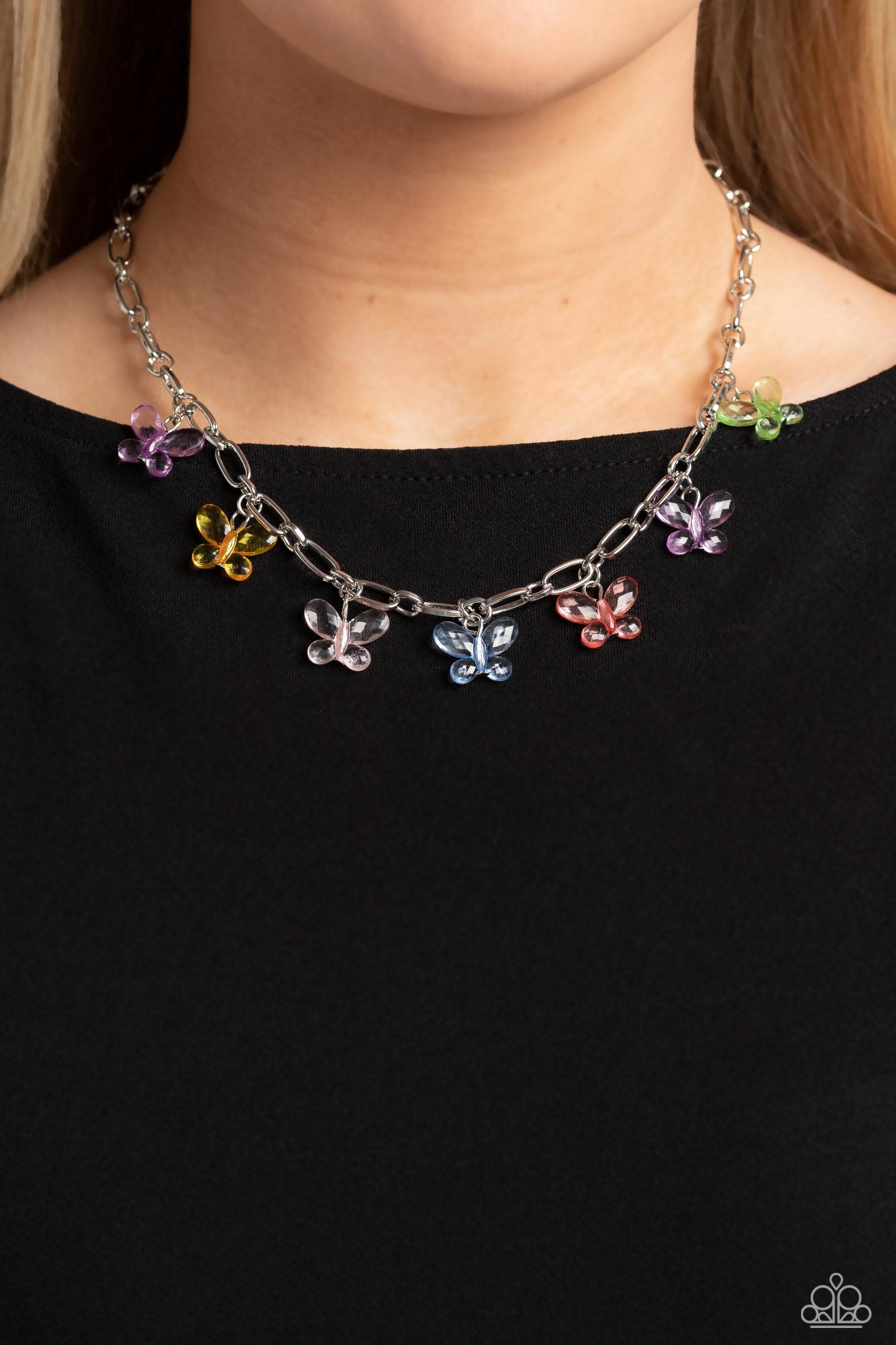 Fluttering along a silver paperclip chain, a glassy collection of colorful butterflies whimsically connects below the collar for an enchanting fashion. Features an adjustable clasp closure.  Sold as one individual necklace. Includes one pair of matching earrings.