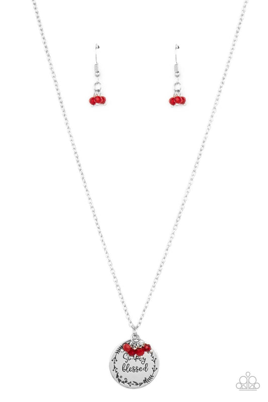 Bordered in a leafy pattern, a shiny silver disc is stamped with the phrase, "Simply Blessed," joins a dainty cluster of glassy and polished red crystal-like beads at the bottom of a chain, creating an inspirational pendant below the collar. Features an adjustable clasp closure.  Sold as one individual necklace. Includes one pair of matching earrings.