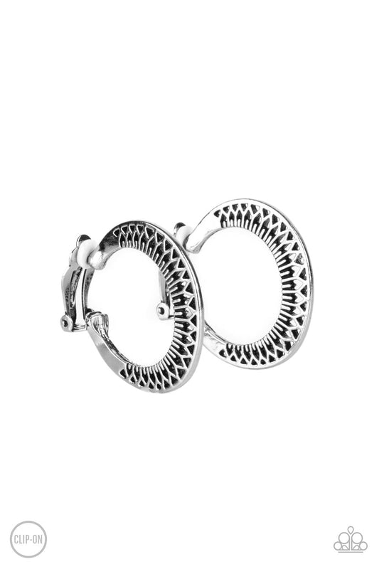 Stenciled in a petal-like texture, a silver frame delicately curves into a floral patterned hoop. Earring attaches to a standard clip-on fitting. Hoop measures approximately 1 1/2" in diameter.  Sold as one pair of clip-on earrings.