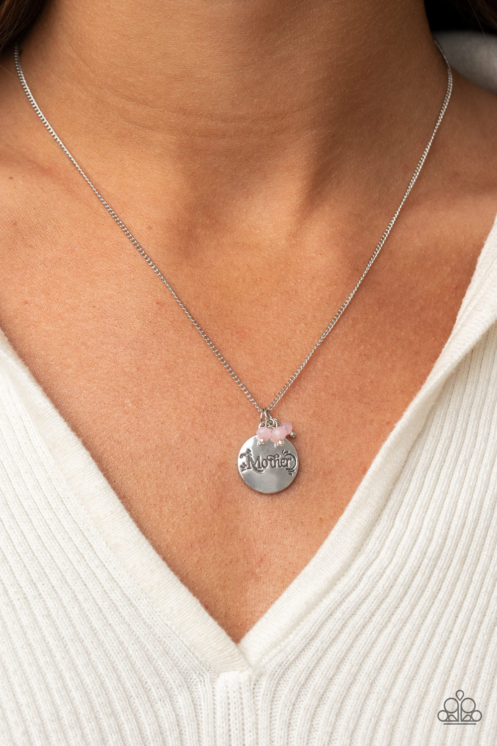 A dainty cluster of opaque pink beads delicately joins a shiny silver disc stamped in the word, "Mother," along a classic silver chain, creating a whimsical pendant below the collar. Features an adjustable clasp closure.  Sold as one individual necklace. Includes one pair of matching earrings.\
