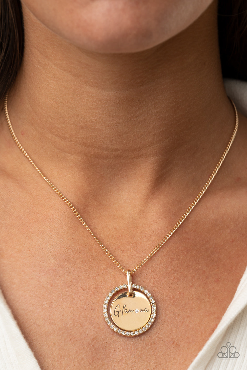 Infused with a gold ring of glassy white rhinestones, a glistening gold disc is dotted with a dainty white rhinestone and stamped in the word, "Glamma," as it swings below the collar for a glamorously sentimental look. Features an adjustable clasp closure.  Sold as one individual necklace. Includes one pair of matching earrings.