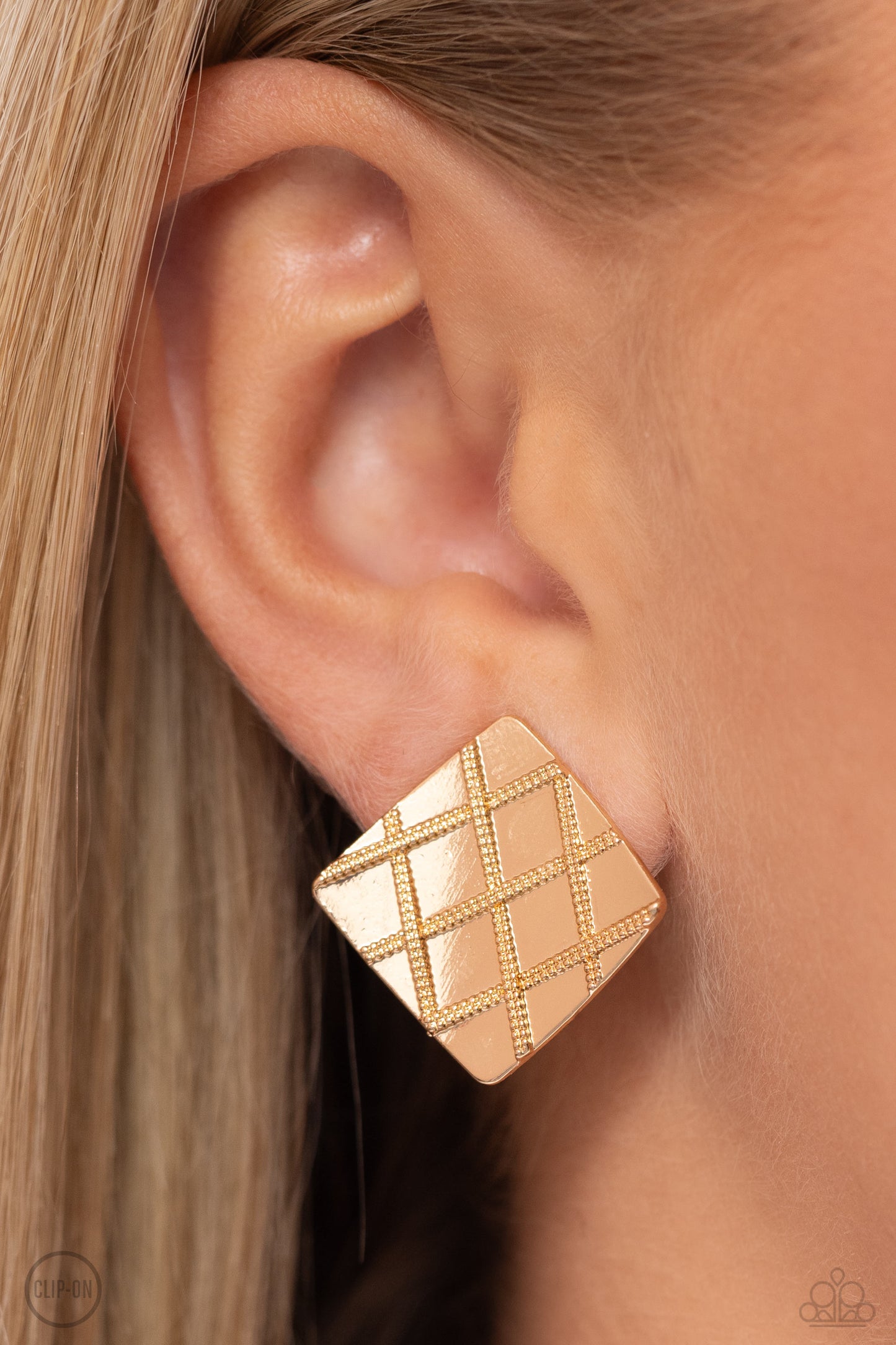A curving gold square is embossed in a slanted plaid-like pattern, creating a tactile frame. Earring attaches to a standard clip-on fitting.  Sold as one pair of clip-on earrings.   Clip On Earring