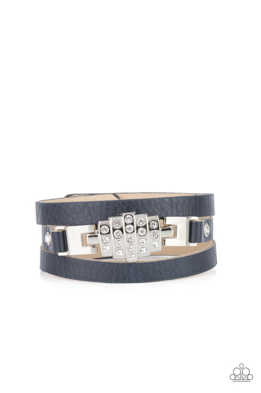 A white rhinestone silver centerpiece is studded in place by white rhinestone encrusted silver studs across the spliced center of a blue leather band, creating a glittery urban look around the wrist. Features an adjustable snap closure.  Sold as one individual bracelet.