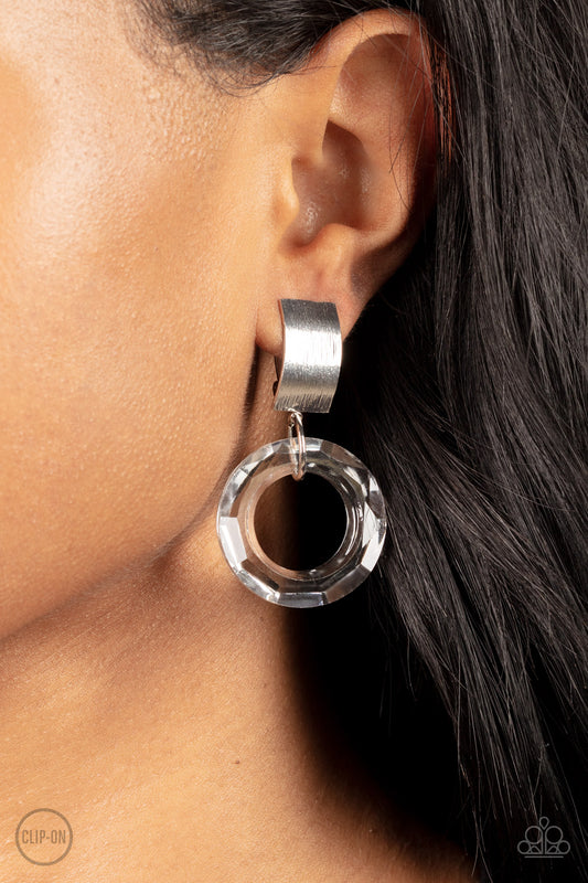 A faceted acrylic ring links to the bottom of a curved silver plate, creating a modern lure. Earring attaches to a standard clip-on fitting.  Sold as one pair of clip-on earrings.   Clip On Earring