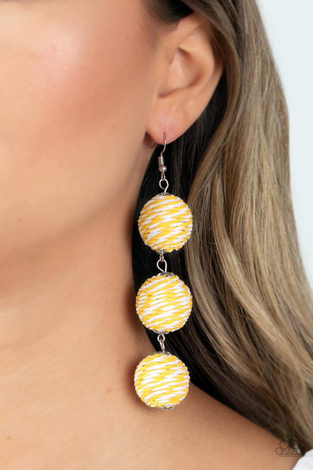 A woven collection of Illuminating and white crepe-like strings ornately wraps around three hanging beads, reminiscent of decorative party lanterns. Earring attaches to a standard fishhook fitting.  Sold as one pair of earrings.