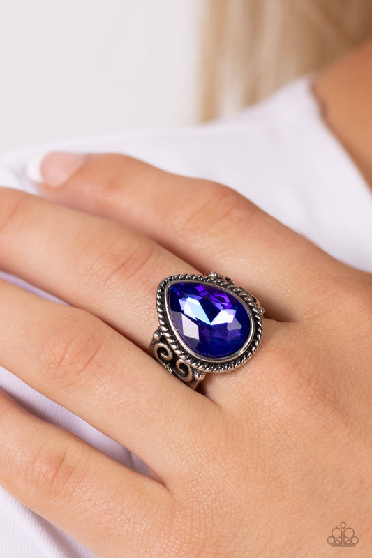 Featuring an iridescent UV finish, an oversized purple teardrop gem is pressed in the center of a textured silver frame atop a thick silver band whirling with silver filigree. Features a stretchy band for a flexible fit. Due to its prismatic palette, color may vary.  Sold as one individual ring.