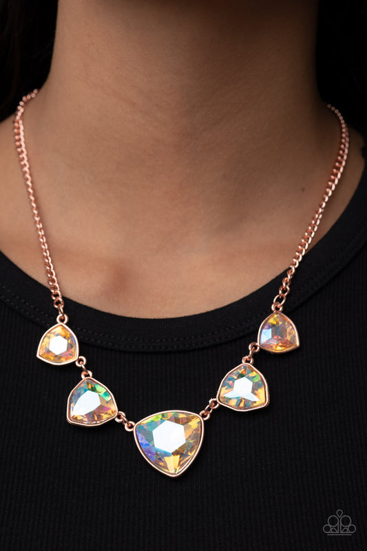 Encased in shiny copper fittings, an oversized collection of iridescent geometric gems gradually increase in size as they link below the collar for a stellar statement. Features an adjustable clasp closure.  Sold as one individual necklace. Includes one pair of matching earrings.