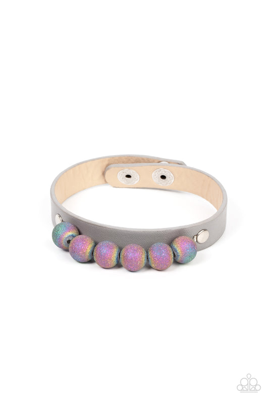 Brushed in shimmering glitter, multicolored beads swirling in an oil spill finish are threaded along a wire. The colorful collection is layered atop an Ultimate Gray leather band for an out-of-this-world finish. Features an adjustable snap closure.  Sold as one individual bracelet.