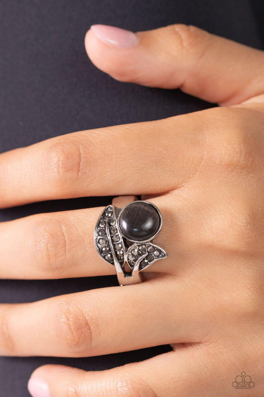 Hematite rhinestone encrusted silver leaf frames delicately gather around a dreamy black cat's eye stone, resulting in an ethereal centerpiece atop the finger. Features a dainty stretchy band for a flexible fit.  Sold as one individual ring.