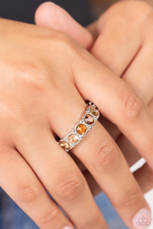 A glitzy collection of topaz, golden topaz, peach, and opal white rhinestones encrusts the front of a studded silver band, result in a sparkly spectrum of color across the finger. Features a dainty stretchy band for a flexible fit.  Sold as one individual ring.