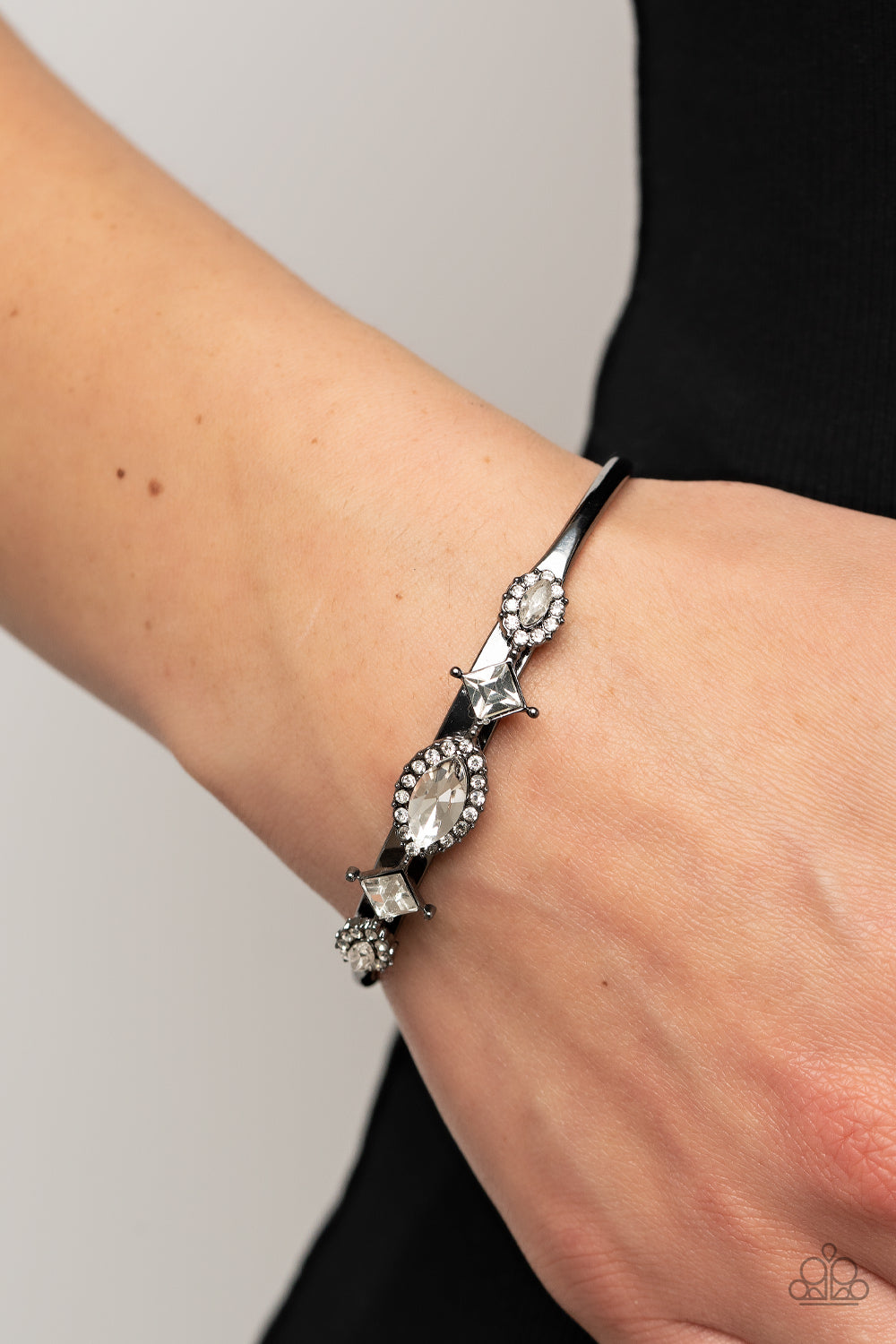 Bordered in glassy white rhinestones, a dainty arrangement of marquise cut rhinestones alternates with tilted square cut rhinestones across the front of a dainty gunmetal cuff for a surprisingly sparkly finish.  Sold as one individual bracelet.