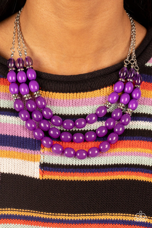 Infused with silver accents, rows of glassy, opaque, and acrylic purple beads are threaded along invisible wires at the bottom of silver chains that layer into a vivacious pop of color below the collar. Features an adjustable clasp closure.  Sold as one individual necklace. Includes one pair of matching earrings.   Get The Complete Look! Bracelet: "Coastal Coastin' - Purple" (Sold Separately)
