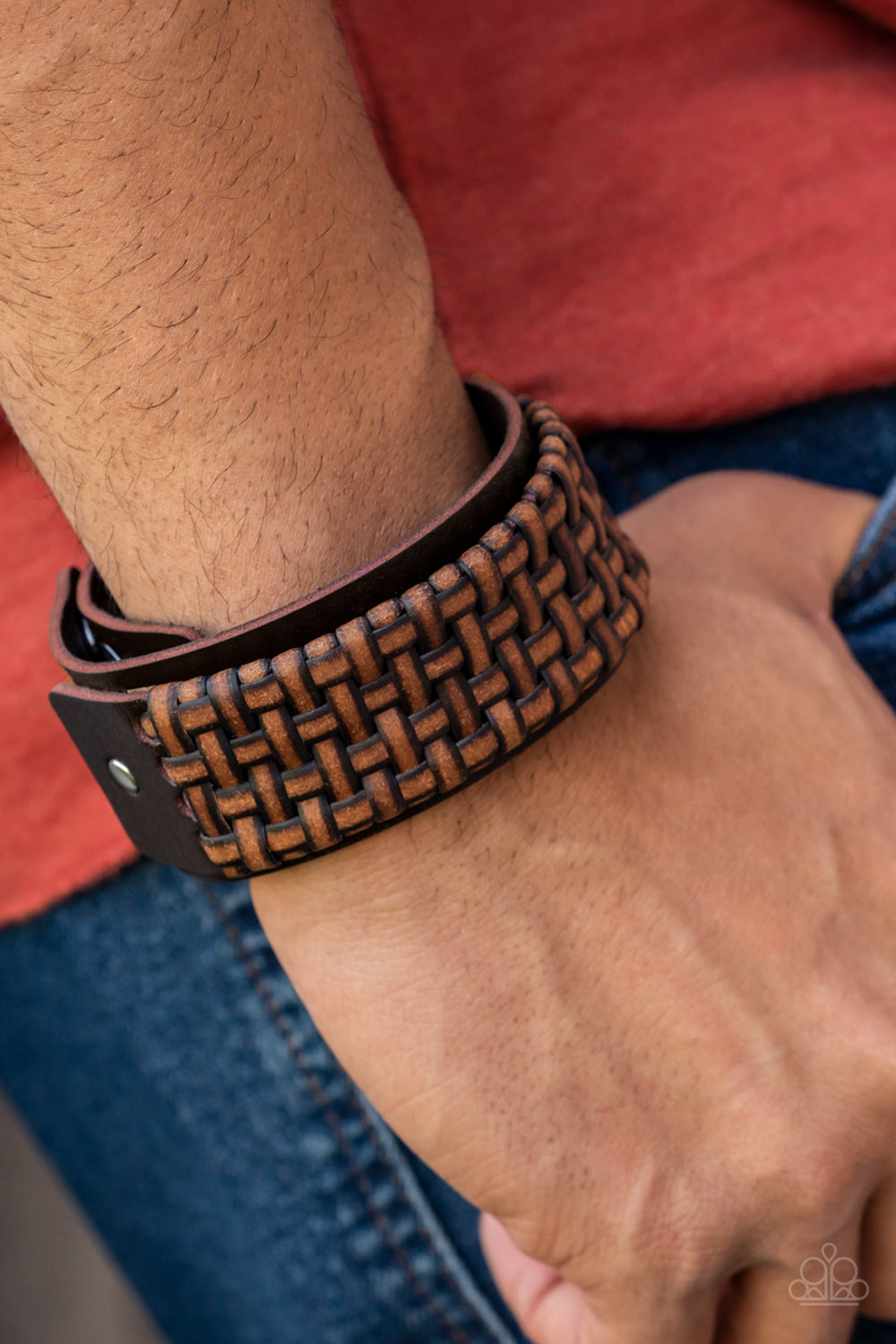 Distressed leather laces weave into a wicker-like pattern, creating a thick band of texture that wraps around a leather band. The textured overlay is studded in place across the front of the brown leather band, resulting in a rustic centerpiece. Features an adjustable snap closure.  Sold as one individual bracelet.
