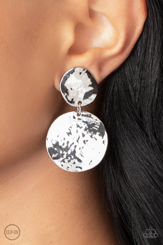 Hammered with high-sheen texture, warped silver discs delicately link into a bold monochromatic statement piece. Earring attaches to a standard clip-on fitting.  Sold as one pair of clip-on earrings.  Clip On Earring