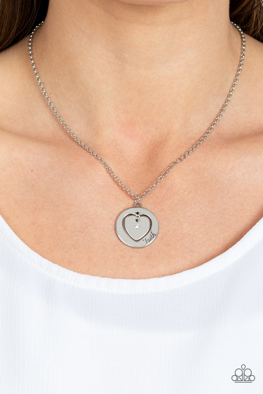 Dotted with a dainty white rhinestone, a silver heart charm swings freely inside of a heart-cutout silver frame. Stamped in the word, "Faith," the inspirational pendant falls just below the collar for a sentimental finish. Features an adjustable clasp closure.  Sold as one individual necklace. Includes one pair of matching earrings.