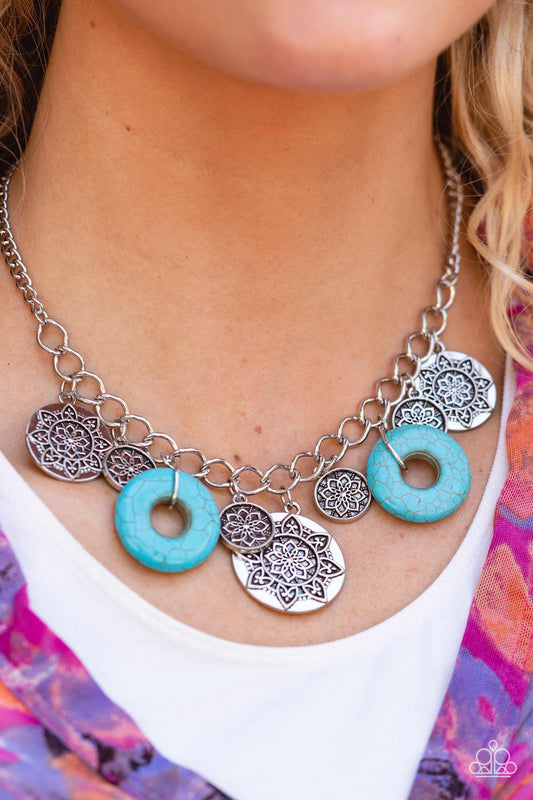 A collection of silver discs, embellished with intricate mandala-like designs, dances along a thick silver chain, with a pair of polished turquoise stone rings adding a pop of color to the rustic design. Features an adjustable clasp closure.  Sold as one individual necklace. Includes one pair of matching earrings.