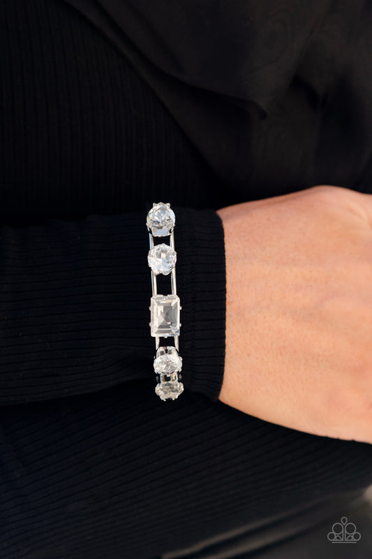 Set in elevated, silver-pronged settings, an oversized collection of white gems adorns the top of an airy silver cuff. Featuring various shapes, the oversized collection showcases endless light-catching texture across its faceted surface, creating blinding bling atop the wrist.  Sold as one individual bracelet.