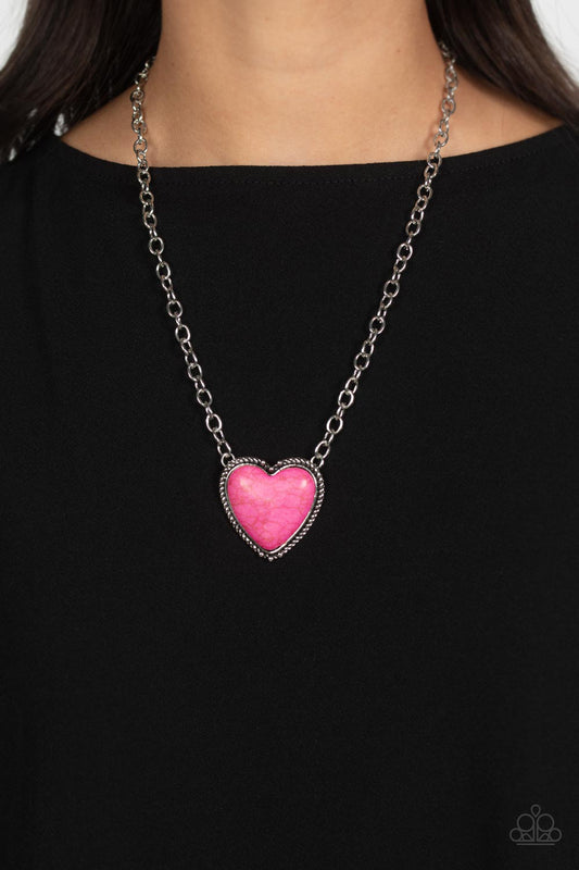 Dangling from the bottom of a thick silver chain, an oversized, hot pink stone is pressed into a textured, studded, silver heart frame for some southwestern sass. Features an adjustable clasp closure. As the stone elements in this piece are natural, some color variation is normal.  Sold as one individual necklace. Includes one pair of matching earrings.