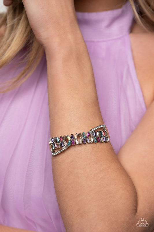 Modeled after the infinity symbol curves, a row of dainty white rhinestones playfully interacts with emerald-cut gems splashed in shades of amethyst, light blue, pink, smoked topaz, and iridescence. Set in clusters of three, the emerald-cuts haphazardly stack on top of one another for a timeless, geometric radiance atop the wrist. Due to its prismatic palette, color may vary. Features a hinged closure.  Sold as one individual bracelet.