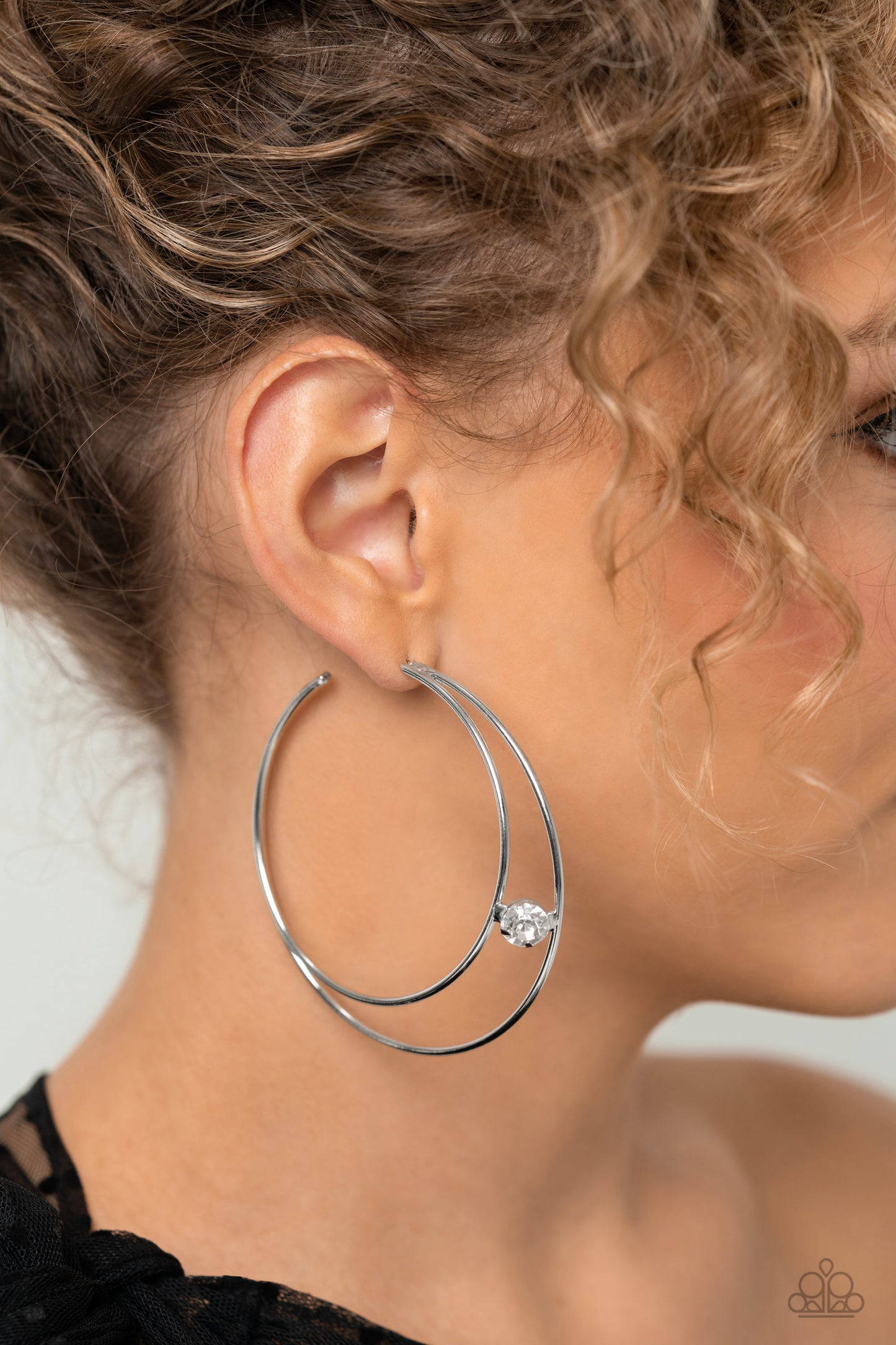 Lodged between two dainty silver crescent frames that curve into double hoops, a faceted white rhinestone rests for a delicate shimmer near the ear. Earring attaches to a standard post fitting. Hoop measures approximately 2" in diameter.  Sold as one pair of hoop earrings.