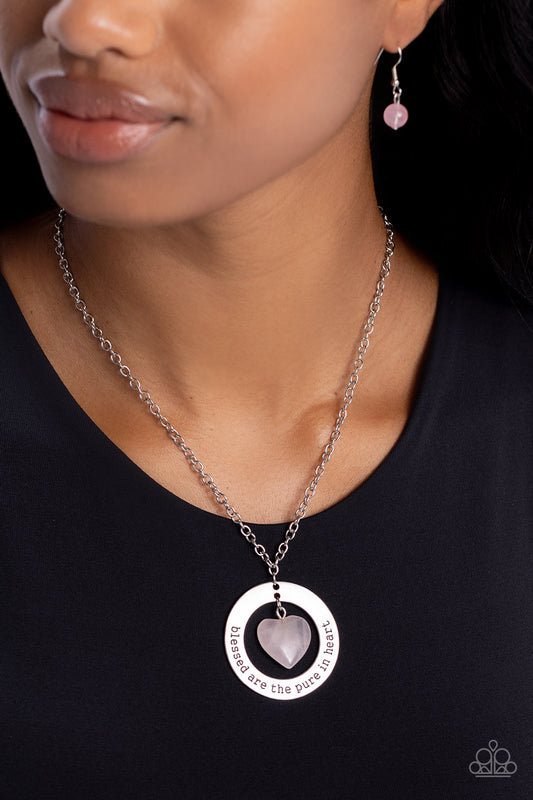 A pink stone heart swings from the bottom of an oversized silver hoop fitting, creating a simplistically earthy pendant at the bottom of a classic silver chain. The phrase "blessed are the pure in heart" is stamped along the curve of the silver hoop frame, finishing the design off with an inspirational finish. Features an adjustable clasp closure. As the stone elements in this piece are natural, some color variation is normal.     Sold as one individual necklace. Includes one pair of matching earrings.
