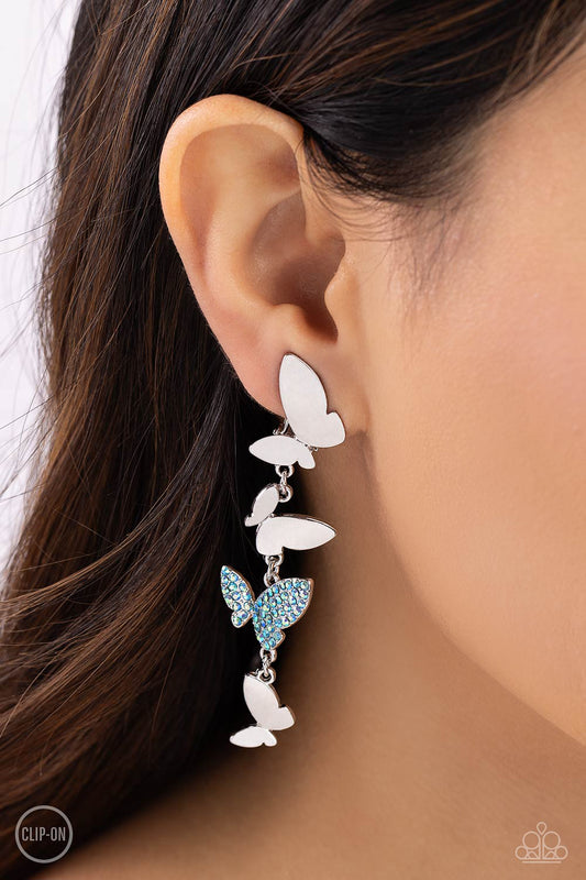 Three butterflies with high-sheen silver wings and one blue iridescent-encrusted butterfly flutter down the ear, creating a free-spirited lure. Each butterfly swings in whimsical asymmetry, creating the look of butterflies flying in alternating directions. Earring attaches to a standard clip-on fitting. Due to its prismatic palette, color may vary.  Sold as one pair of clip-on earrings.