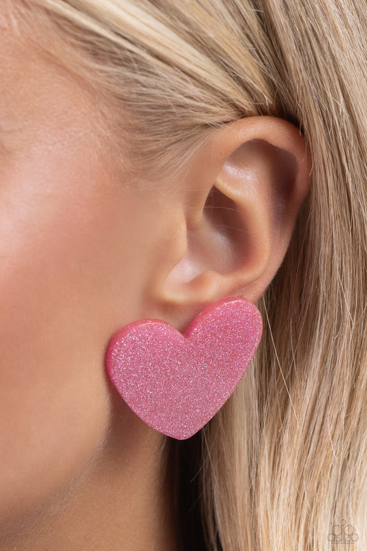 Dusted in sparkles, a hot pink acrylic flat heart frame shimmers and shines from the ear for a flirtatious finish. Earring attaches to a standard post fitting.  Sold as one pair of post earrings.