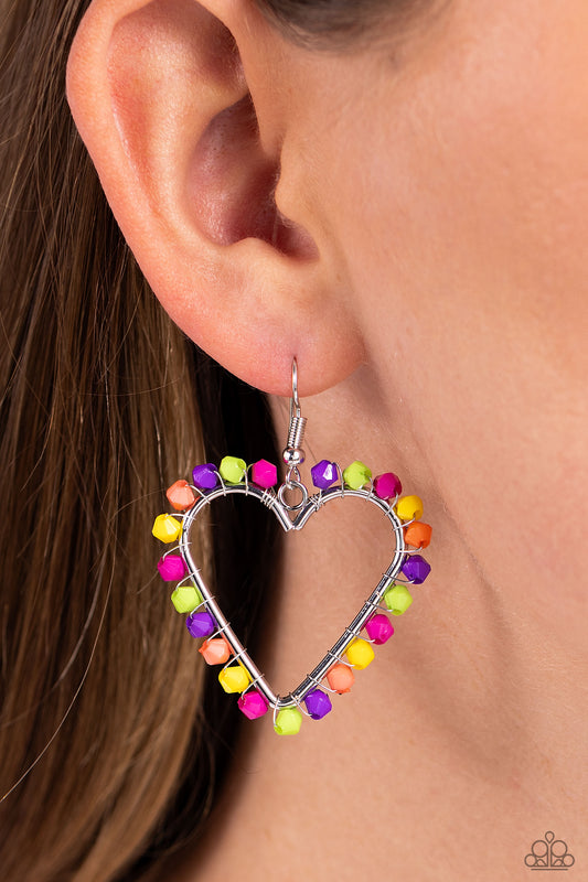 A vibrant collection of Rose Violet, Kohlrabi, purple, yellow, and coral seed beads are wrapped along the outside curve of a shiny, silver heart frame by shimmery silver wire for a handcrafted, fun-loving finish. Earring attaches to a standard fishhook fitting.  Sold as one pair of earrings.
