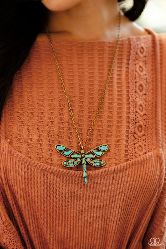 Featuring a classic brass chain, various cuts of turquoise stone are passed into an oversized, airy brass dragonfly pendant for a rustically earthy centerpiece. Features an adjustable clasp closure. As the stone elements in this piece are natural, some color variation is normal.  Sold as one individual necklace. Includes one pair of matching earrings.