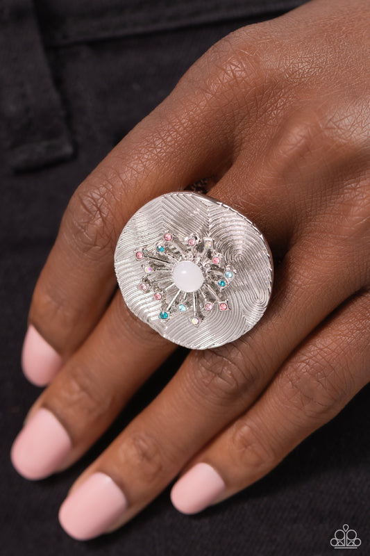 Featuring an oversized, textured backdrop, a dainty 3D sunburst detail, glistening with pink, blue, and iridescent rhinestones, and a white opalescent center standout atop the finger for a sunny pop of color. Features a stretchy band for a flexible fit. Due to its prismatic palette, color may vary.  Sold as one individual ring.