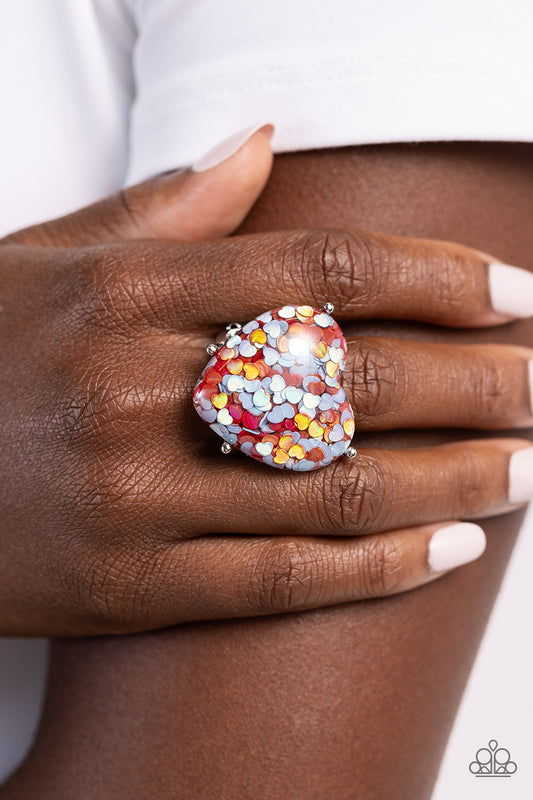 Encased within an exaggerated heart frame, dainty red and blue hearts with flecks of iridescence pattern into a kaleidoscope of color atop the finger on airy bands for a flirty finish. Features a stretchy band for a flexible fit. Due to its prismatic palette, color may vary.  Sold as one individual ring.