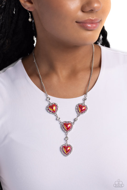 Pressed in a border of white rhinestones and silver studs, iridescent-brushed red hearts delicately link below the collar in a charming, extended fashion. Solitaire white gems alternate between each heart frame for additional shimmer. Features an adjustable clasp closure. Due to its prismatic palette, color may vary.  Sold as one individual necklace. Includes one pair of matching earrings.