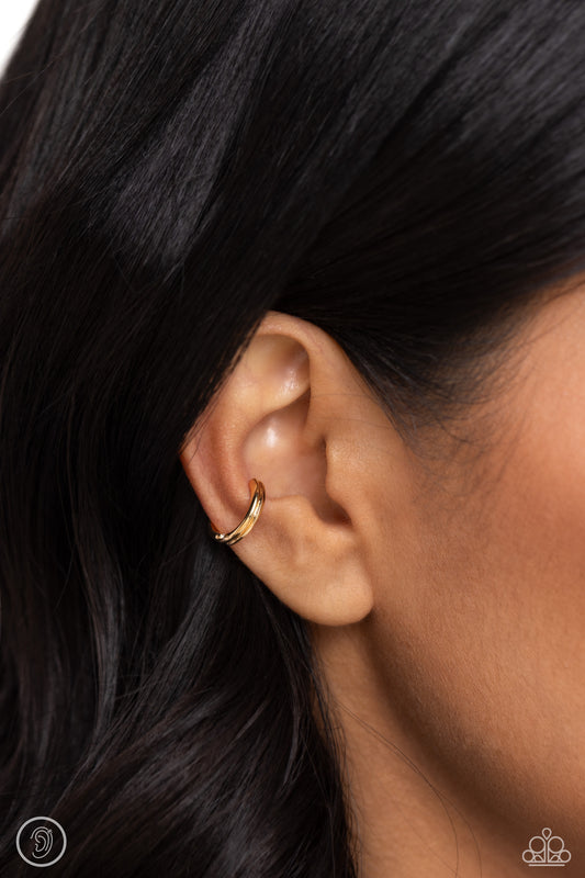 Featuring tapered, textured ends, a thin gold bar curls around the ear for a simplistic statement. Features a smooth surface for sliding ability to desired position on the ear. Due to its structure, adjusting capability is limited.  Sold as one pair of cuff earrings.   Ear Cuff