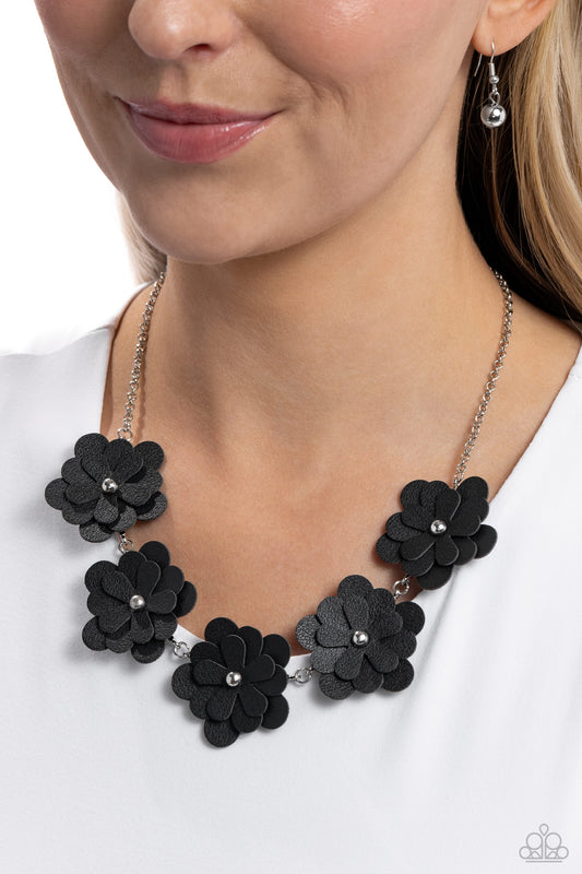 <p>Featuring silver stud centers, a collection of 3D black leather flowers connect to a classic silver chain for a ruggedly retro look. Features an adjustable clasp closure.</p> <p><i> Sold as one individual necklace. Includes one pair of matching earrings.</i></p>