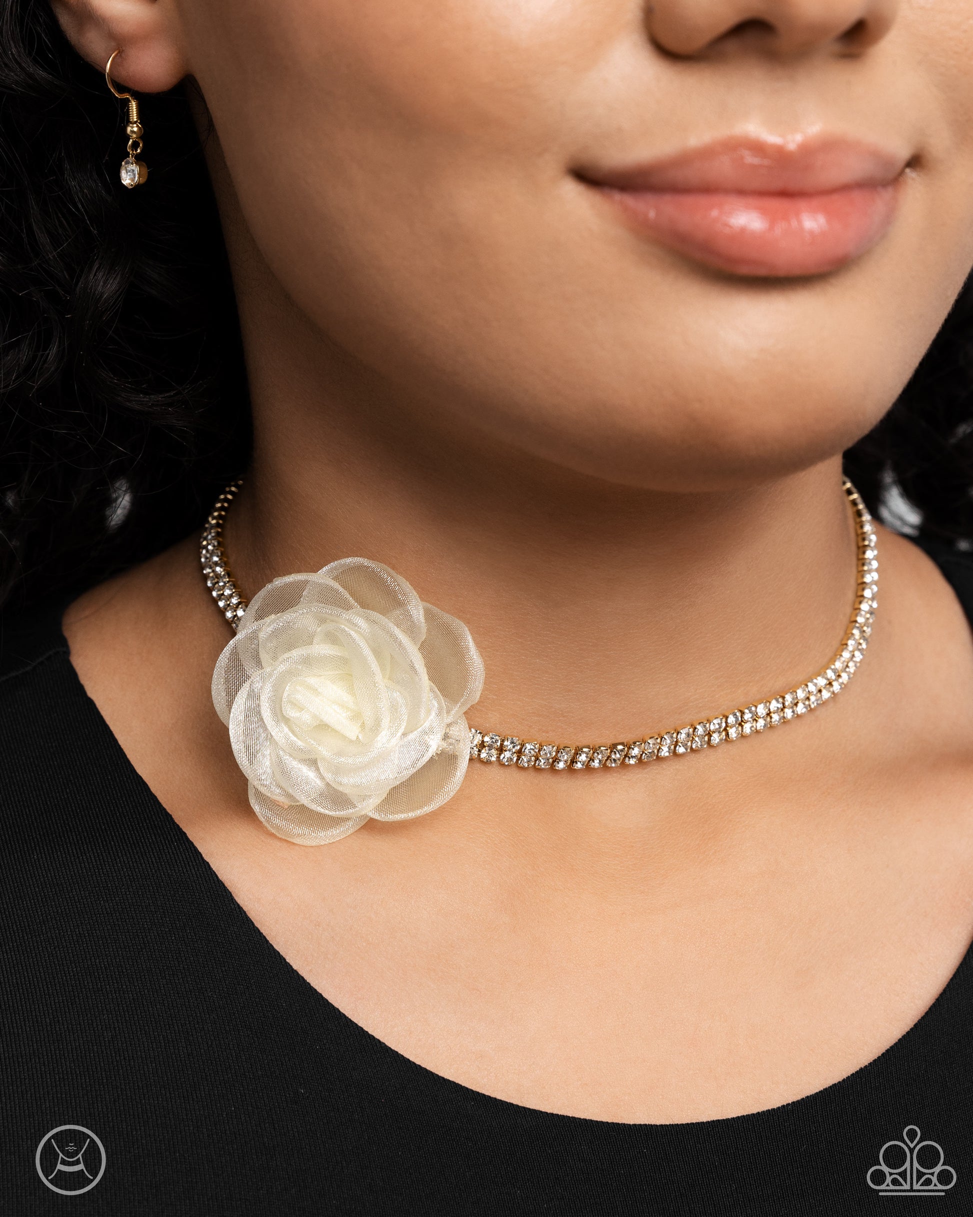 <p>A double-stranded gold chain is embellished with two rows of glistening white rhinestones as it wraps around the collar. An ivory tulle rosette is placed in the center of the design for a floral finish. Features an adjustable clasp closure.</p> <p><i>Sold as one individual choker necklace. Includes one pair of matching earrings. </i></p> &nbsp;<img src="https://d9b54x484lq62.cloudfront.net/paparazzi/shopping/images/517_chokericon_1.jpg" alt="Choker" align="middle" height="50" width="50">